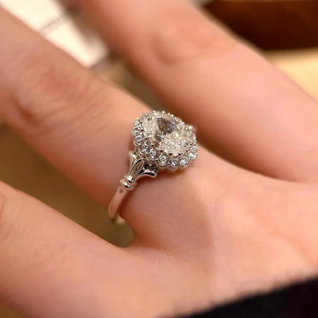 Silver geometric ring with a large diamond detail and adjustable opening on a woman's index finger.