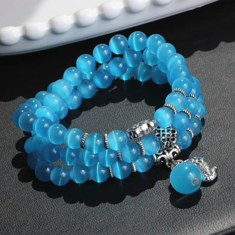 Women's opal bracelet with a Cat Eye charm, shown in one of six colours, wound three times around a wrist.