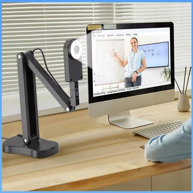 USB computer webcam with built-in microphone on a desk next to a monitor