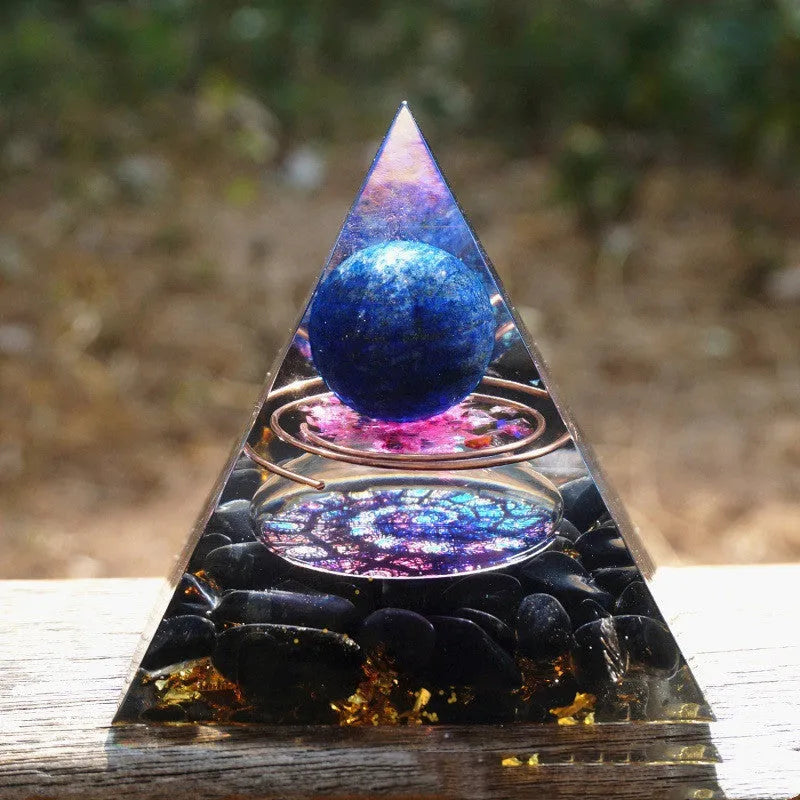 Small 6cm high clear epoxy resin pyramid ornament filled with colourful natural crystal gravel on a shelf.
