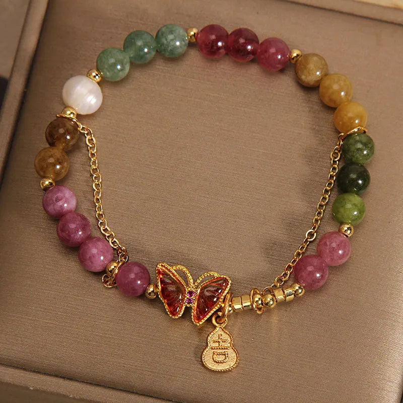 Close-up of a women's agate bracelet with a green tourmaline butterfly-shaped gourd charm on a white background.