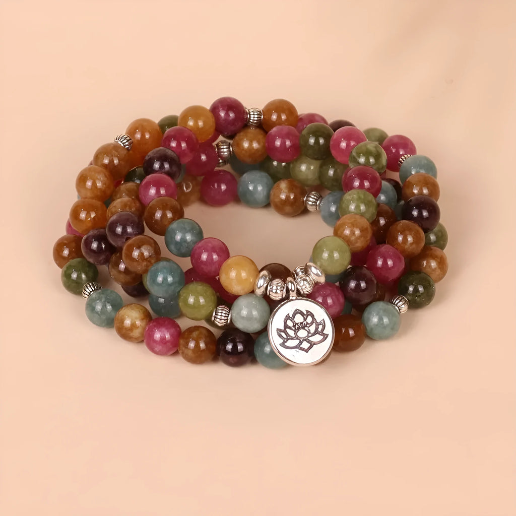 Close-up of a Tourmaline-coloured alloy bracelet with 108 beads and a central hanging lotus decoration.