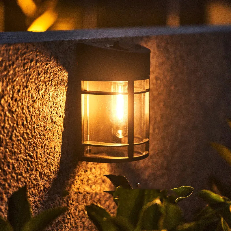 Small white solar-powered outdoor wall light with a dark solar panel on top, mounted on a wall.