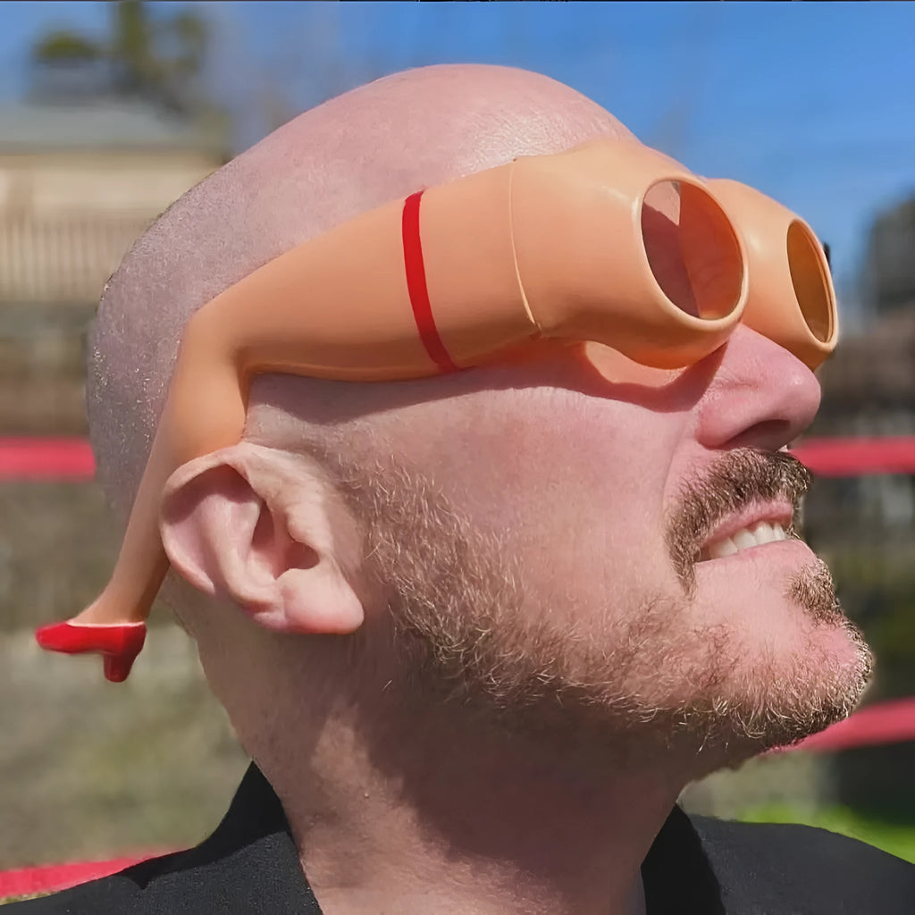 Orange novelty sunglasses with a unique leg hip personality silhouette on a solid background.