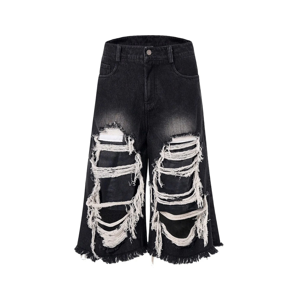 Woman wearing black distressed wide leg cropped jeans with ripped patches.