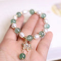 Green geometric strawberry freshwater pearl bracelet with small flower charm and Chinese knot design.