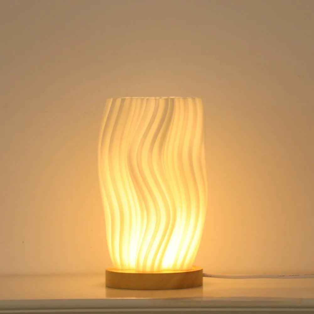 3D printed cylindrical vase night lamp with glass shade in wood colour finish on a bedside table