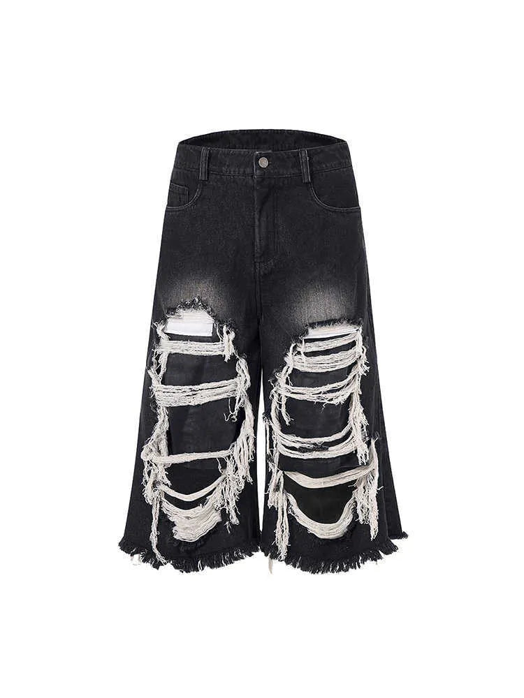 Woman wearing black distressed wide leg cropped jeans with ripped patches.