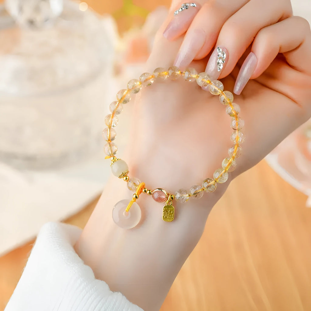 Gold rutilated quartz crystal bracelet with safety buckle and geometric national style design featuring blessing card pendant.