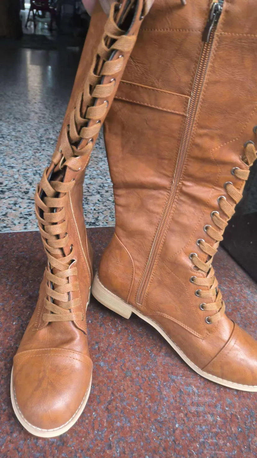Women's black artificial PU knee-high boots with cross strap design on the shaft