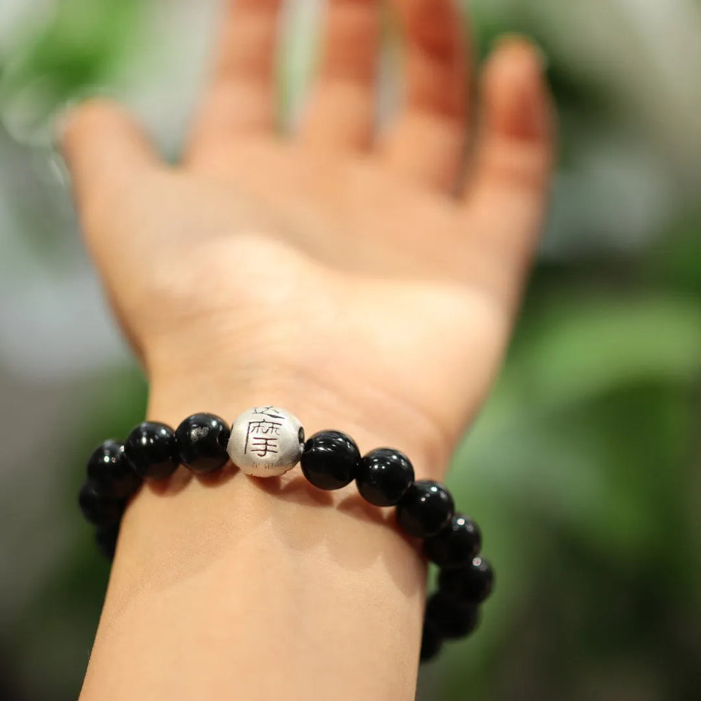 Close-up of a women's bracelet with a large 10mm black agate bead and sterling silver clasp in a Chinese style design.