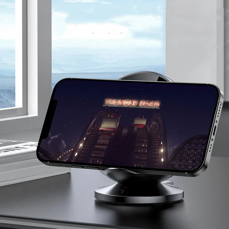 A black multifunctional wireless charging phone holder with integrated Bluetooth speaker on a desk.