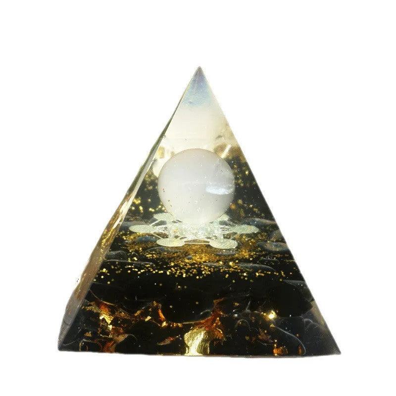 Small 6cm high clear epoxy resin pyramid ornament filled with colourful natural crystal gravel on a shelf.