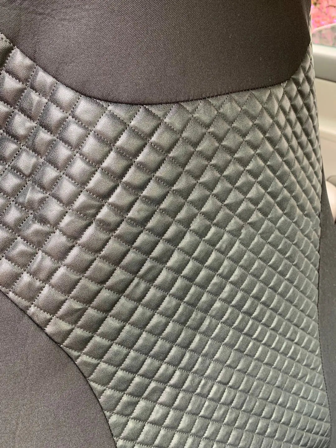 Black quilted automotive seat cover made of PU leather composite material with plastic hooks.