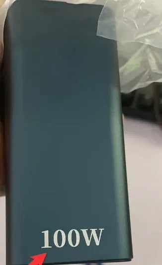 A black metal 65W laptop power bank with 20000mAh capacity, showing size compared to a hand.