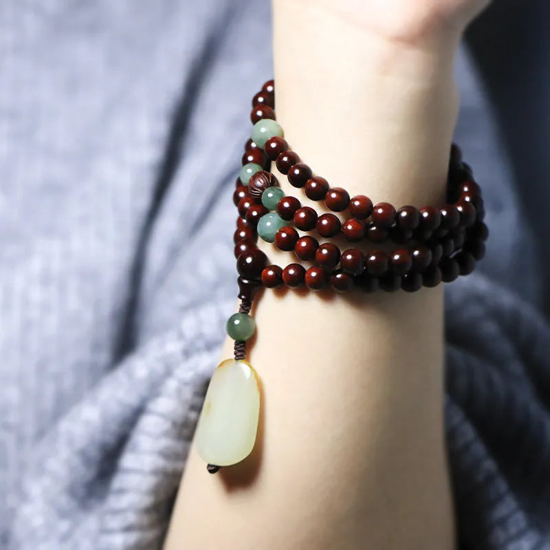 Rosewood beaded bracelet with carved wood elements and green Hotian jade pendant on wrist