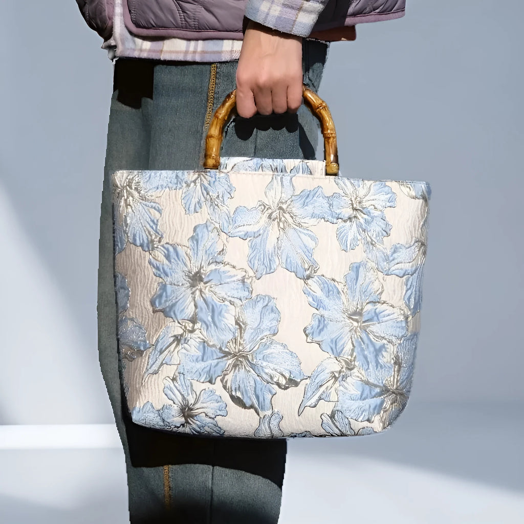 Light blue canvas shoulder bag with bronzing flower print, square shape, and two adjustable connector straps