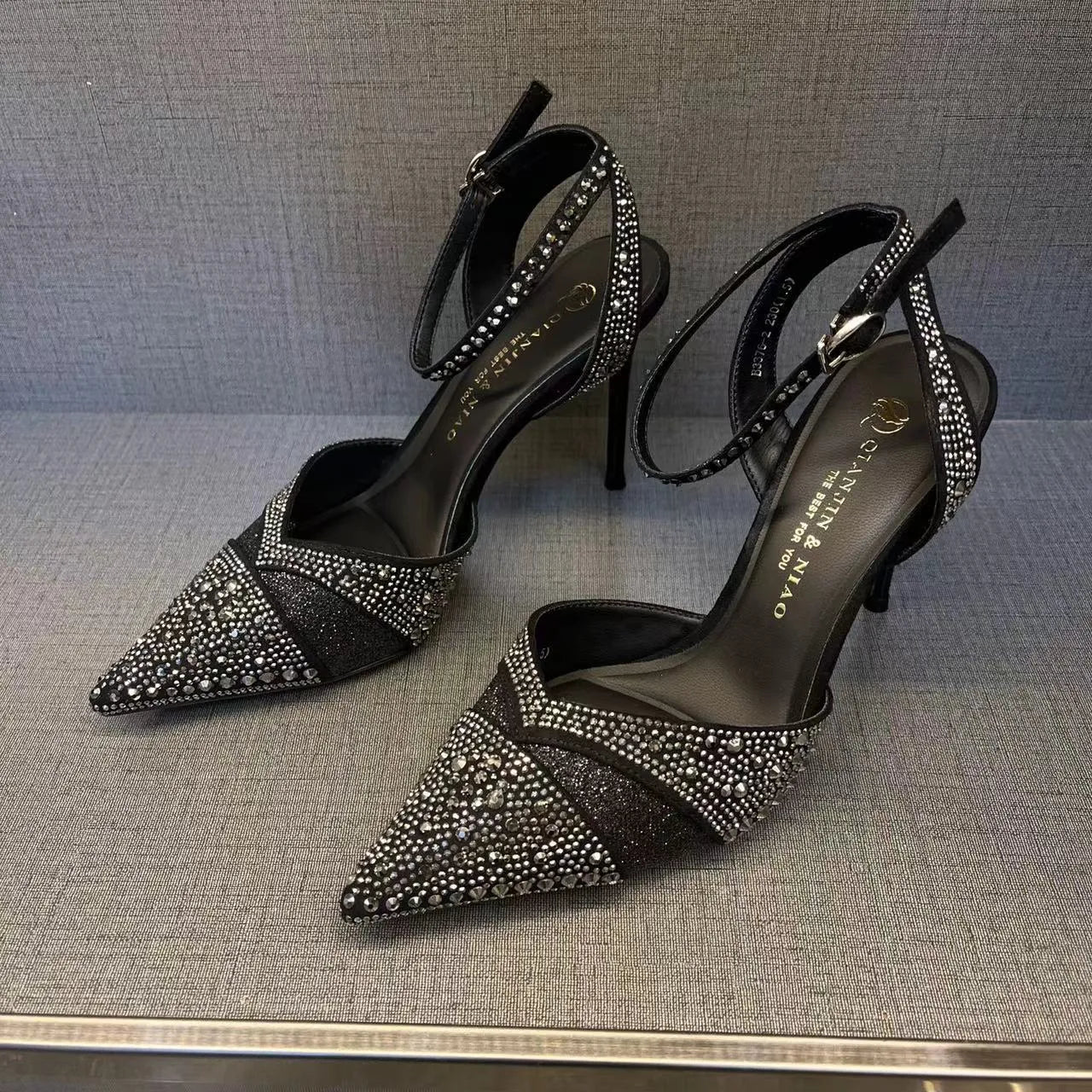 Women's black and silver hollow high heels with a red sole and pointed stiletto toe.