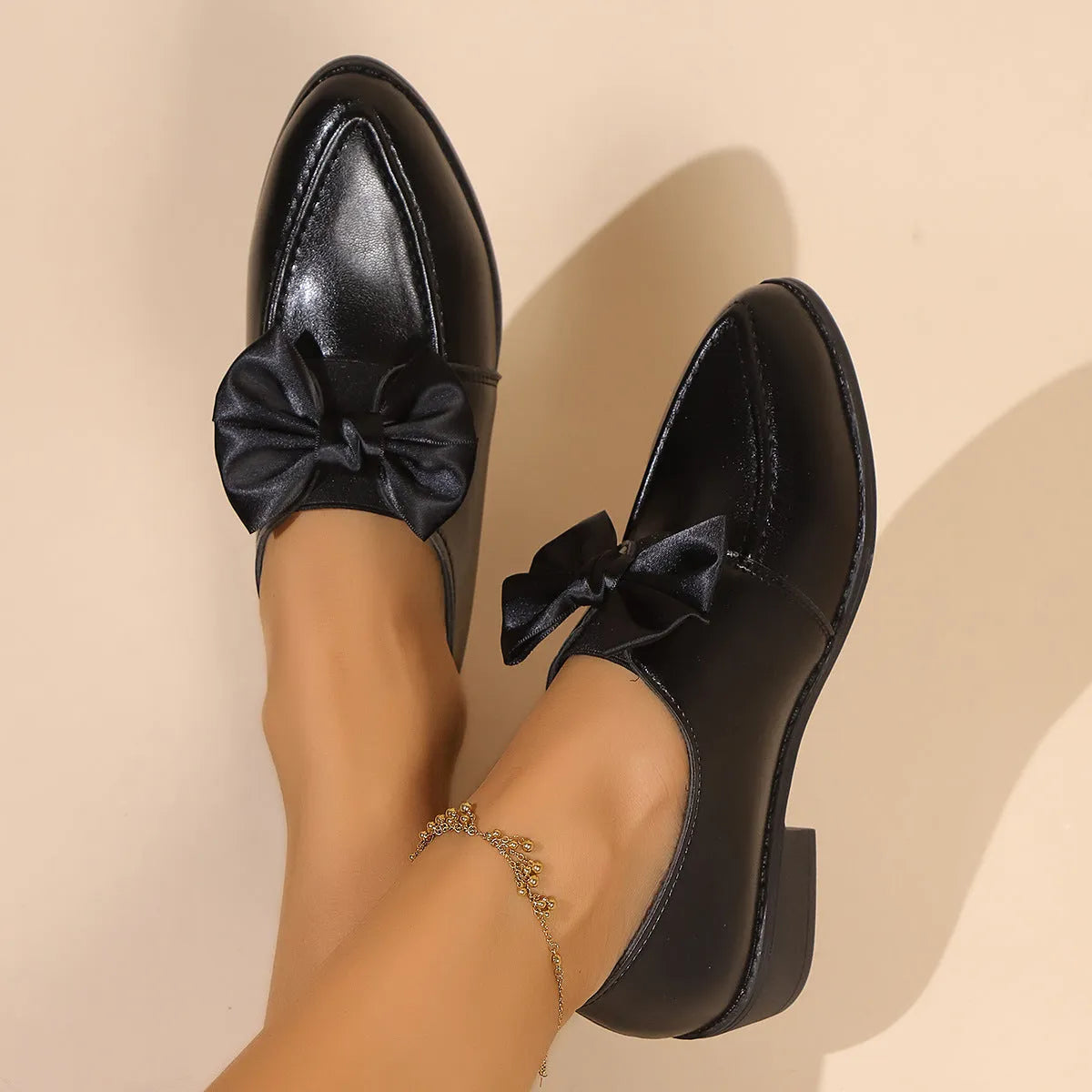 Women's simple leather-look flat shoes with a decorative bow, shown in slip-on style with a rubber sole.