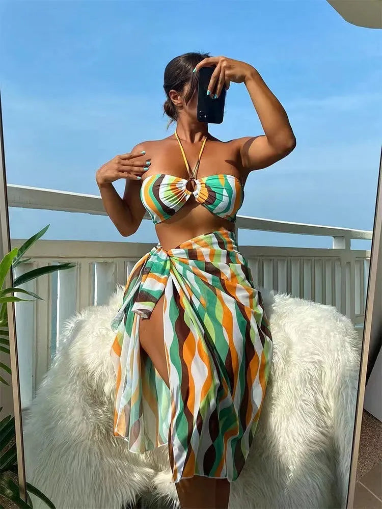 Women's yellow green printed three-piece bikini set with matching beach skirt laid flat.