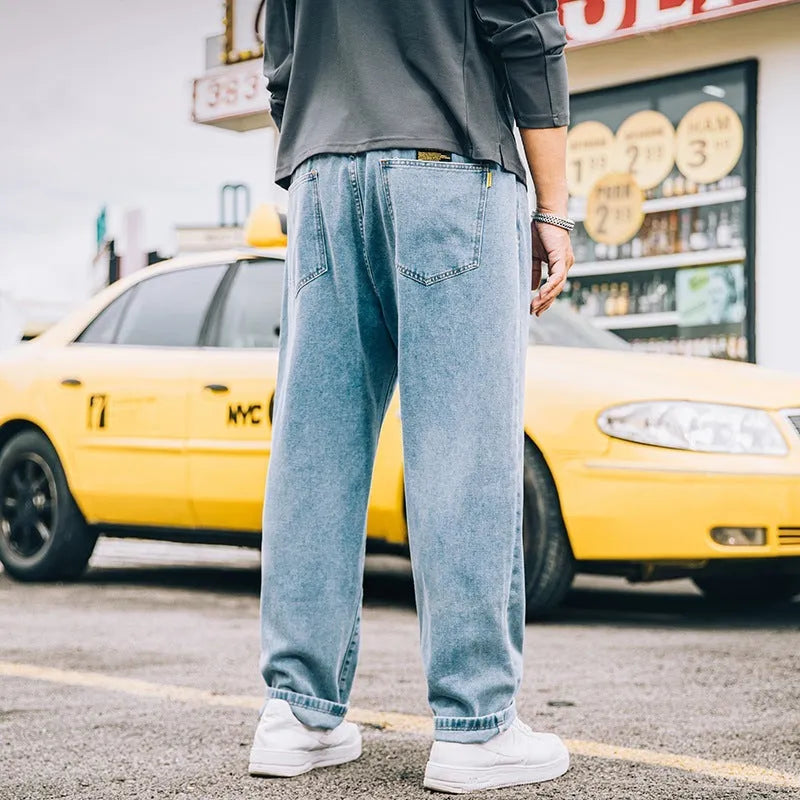 Men's loose straight blue jeans on hanger showing relaxed leg cut and zipper fly