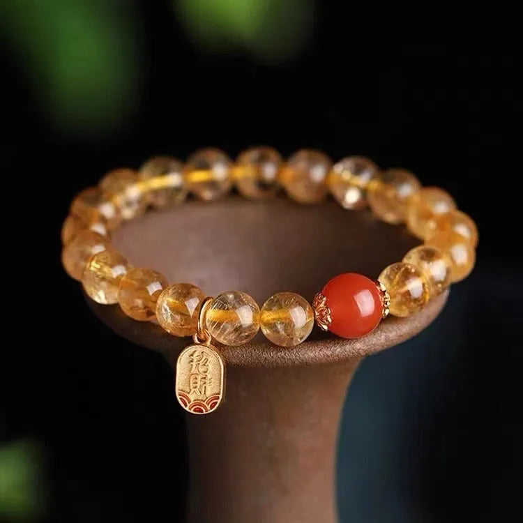 Natural red agate and gold ruby bead bracelet on a wrist, showing polished stones.