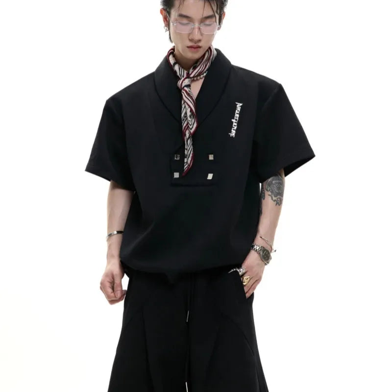 Men's dark grey cotton sports suit with V-neck short sleeve top, padded shoulders, metal embellishments, and matching shorts.