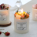 Decorative aromatherapy candle with dried flowers on surface, shown in gift box with chip base.