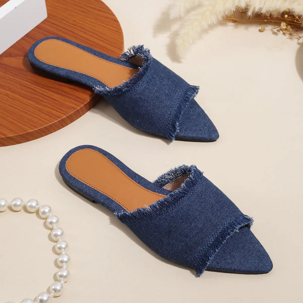 Women's denim slippers with tassel detail and leather lining in various colours on a flat PVC sole.