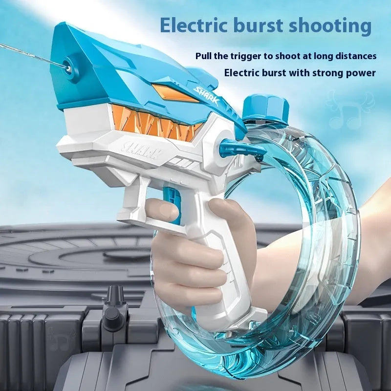 Blue Shark-shaped electric water gun toy with a large tank, placed on a sandy beach.
