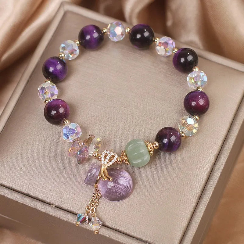 Women's purple Tigereye pendant crystal bracelet with rhinestones on a forest-style background.