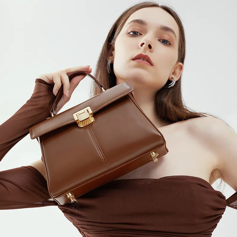 Black leather women's shoulder bag with vachette clasp, shown open to reveal internal zippered pocket.