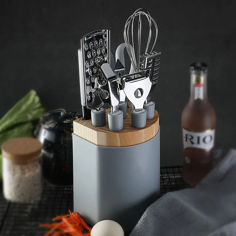 Stainless steel kitchen gadget set with peeler and whisk on grey tray