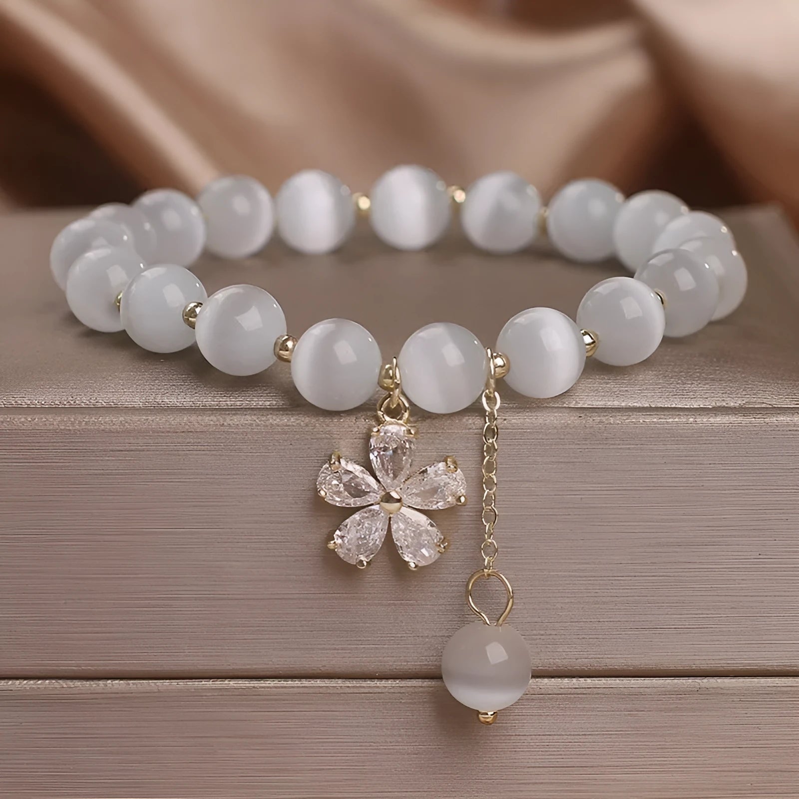 Women's white cat's eye crystal bracelet with flower tassel and morganite safety buckle.