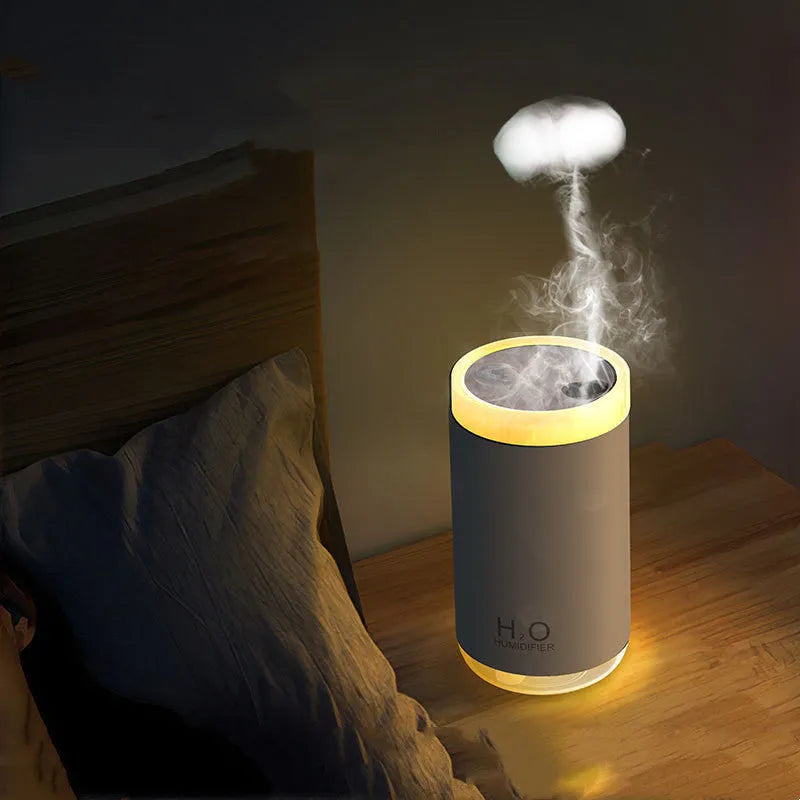 White portable USB humidifier emitting jellyfish-shaped smoke rings with a warm glowing night light on a desk