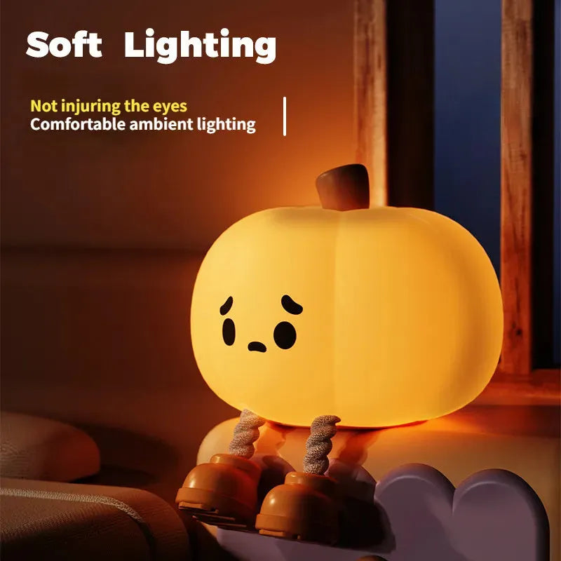 Soft orange silicone pumpkin-shaped night light with a warm glow on a bedside table.