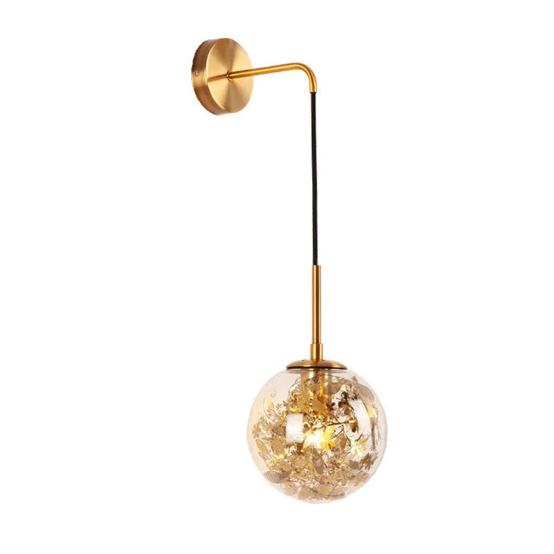 Glass wall lamp with decorative golden flower pattern on a white wall.