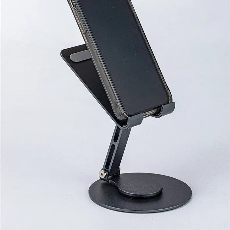 Grey aluminium alloy rotating mobile phone bracket on desk with silica gel grip, 4.8 x 4.2 x 1.4 cm, holding a smartphone in landscape mode