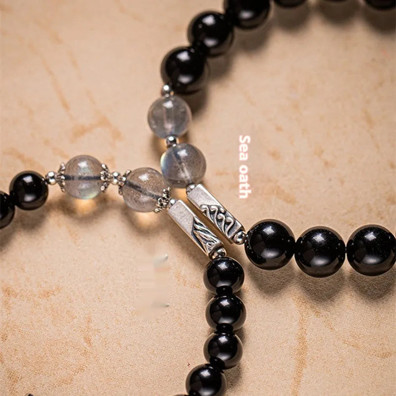 Black obsidian Buddha bead couple bracelets showing 8mm and 10mm sizes on a background.