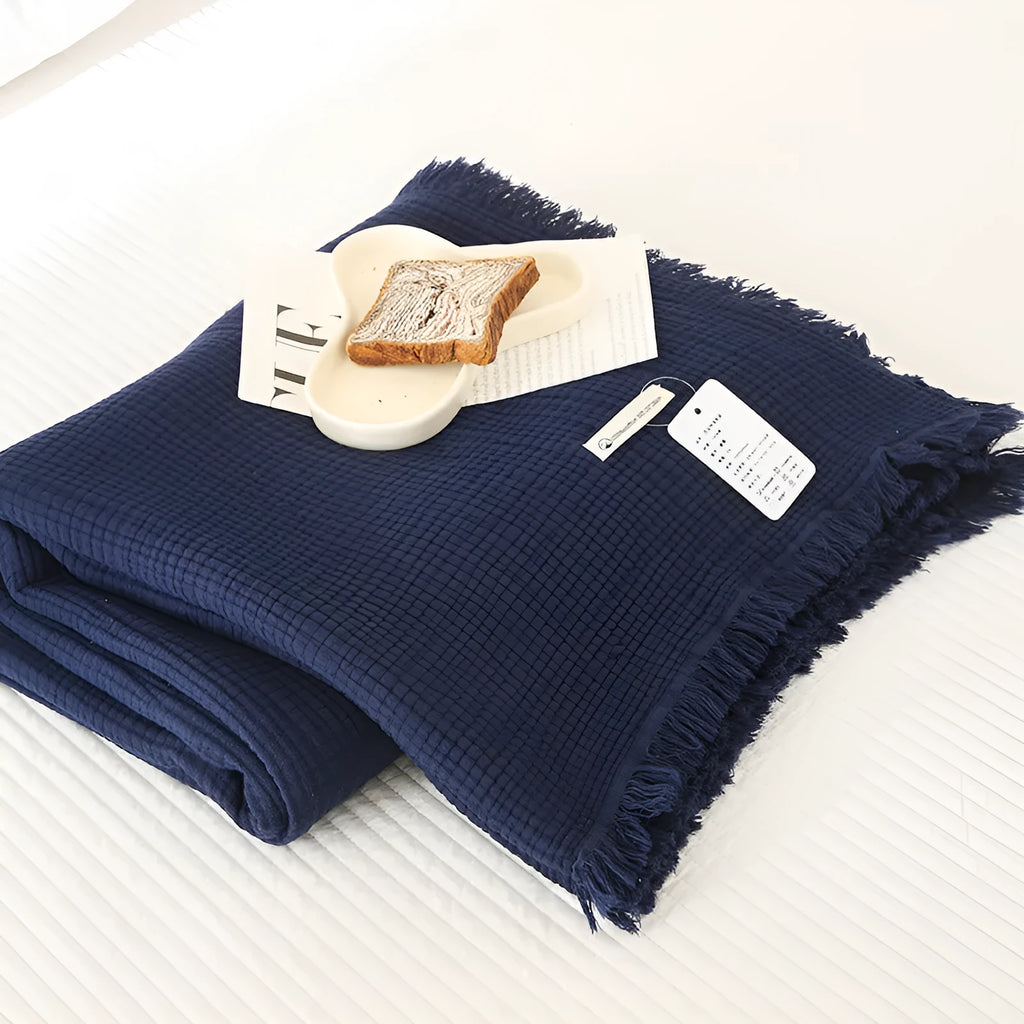 Four-layer cotton gauze blanket with tassel trim shown in avocado green colour.