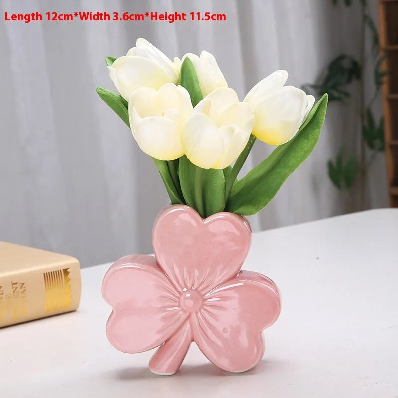 White porcelain clover-shaped ceramic vase in European style, on a desktop.