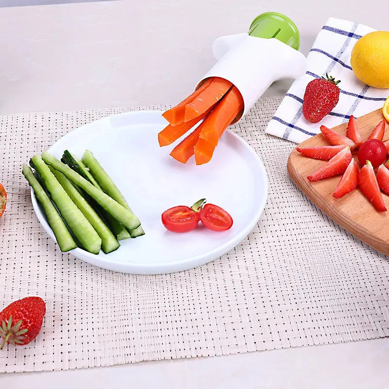 White plastic vegetable and fruit slicer with multiple stainless steel blades for cutting cucumbers, carrots, and strawberries.