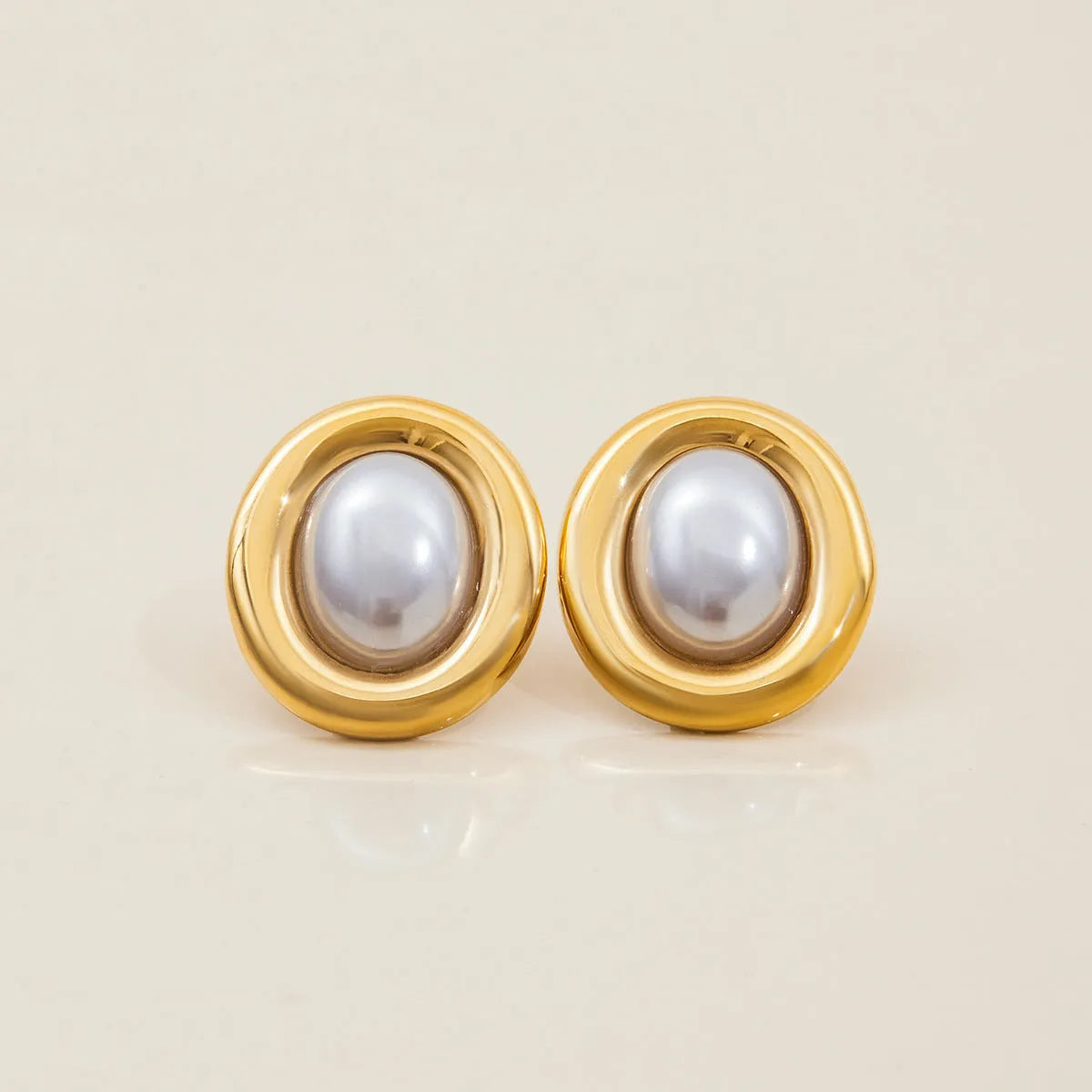 A pair of stainless steel vintage pearl stud earrings with a round pearl and electroplated finish.