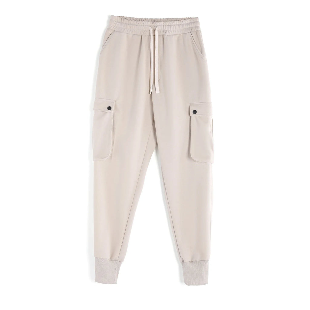 Man wearing loose light grey cotton trousers with ankle-tied cuffs and multiple pockets.