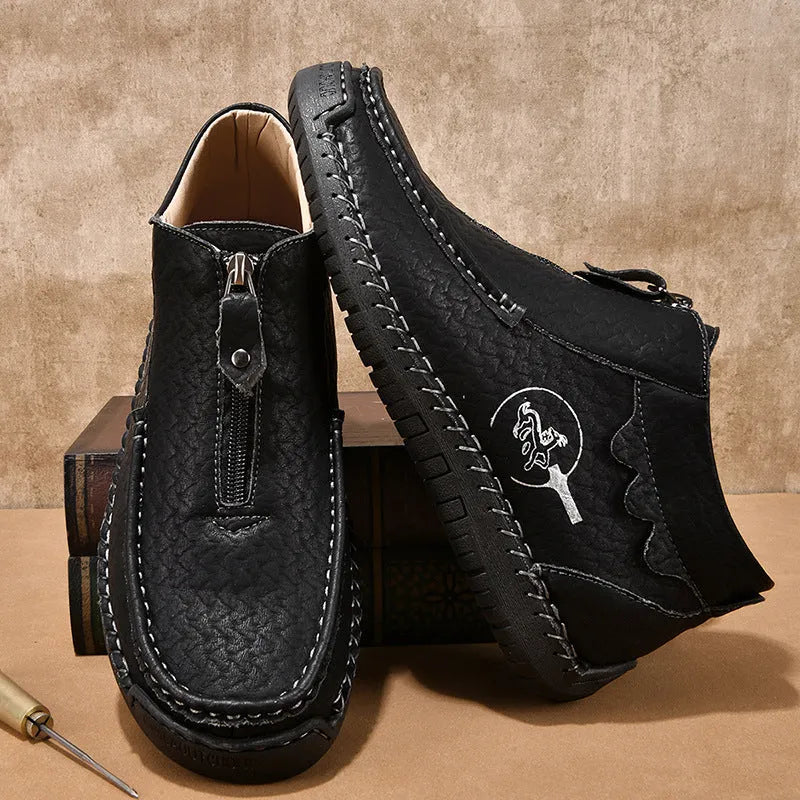Men's black slip-on loafers with a round toe and sewn rubber sole on a grey background.
