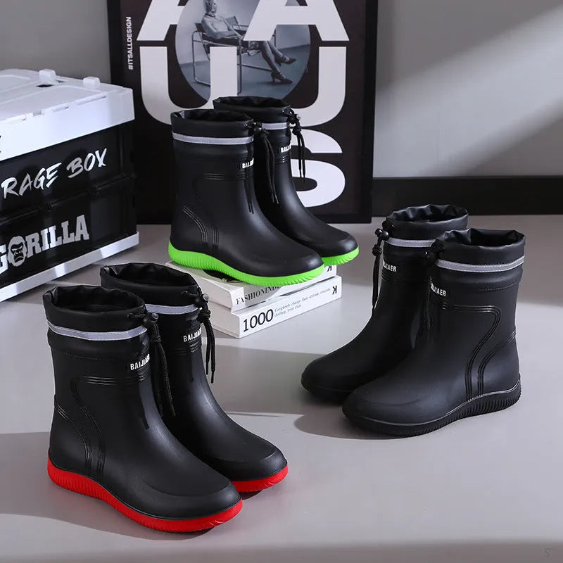 Men's mid-top PVC rain boots in black with green detailing, tassel decoration, and non-slip sole