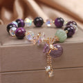 Women's purple Tigereye pendant crystal bracelet with rhinestones on a forest-style background.