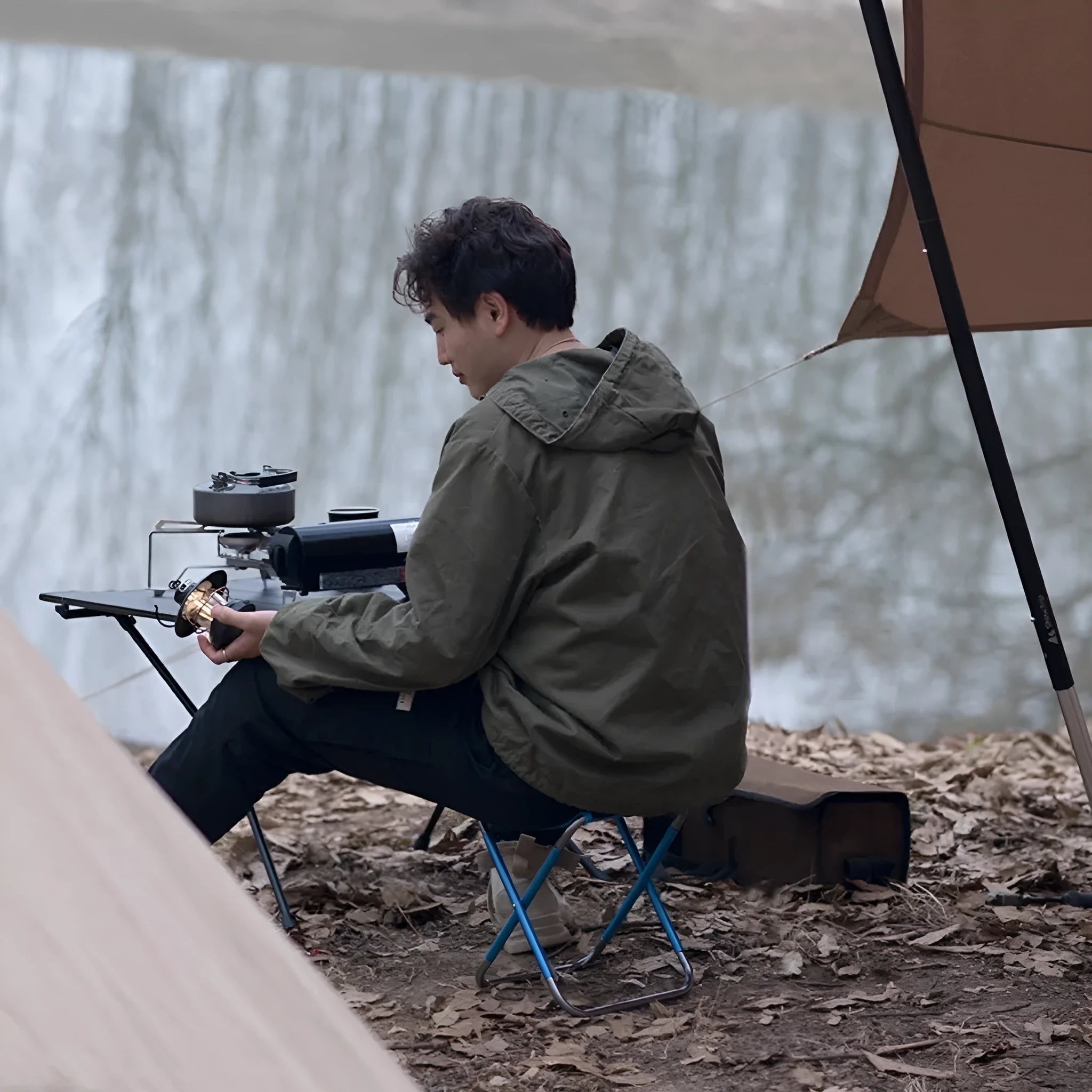 Black aluminium alloy folding camp stool in the open seating position.