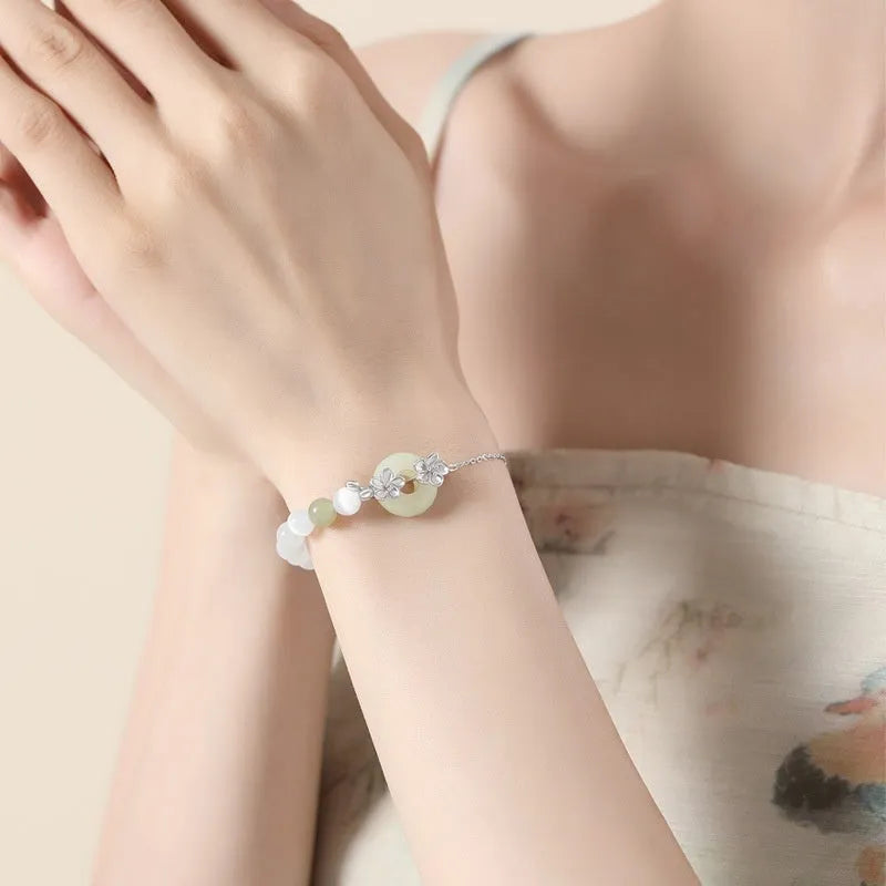 Women's silver peace buckle bracelet with floral design and safety closure mechanism in gold electroplated finish