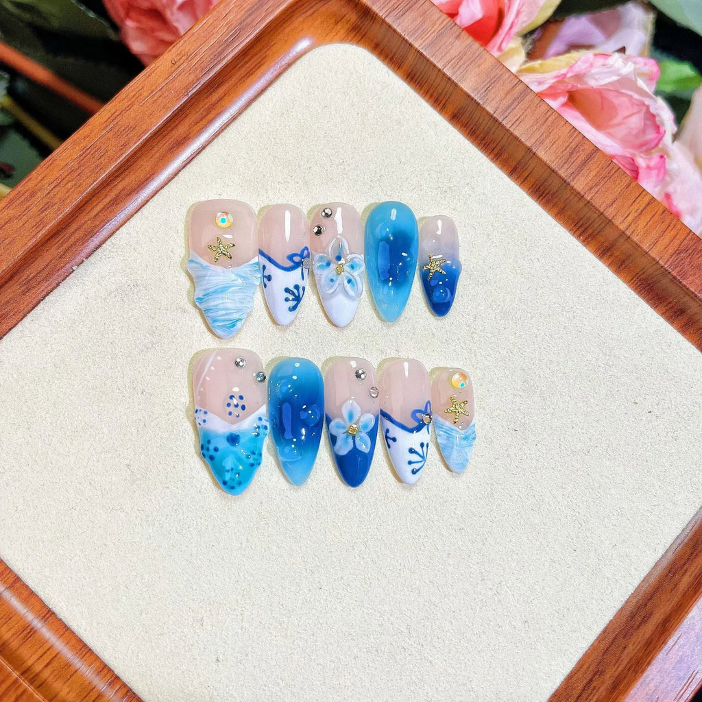Set of 24 blue hand-painted fake nails with carved summer ice transparent design, showing sizes XS, S, M, L.